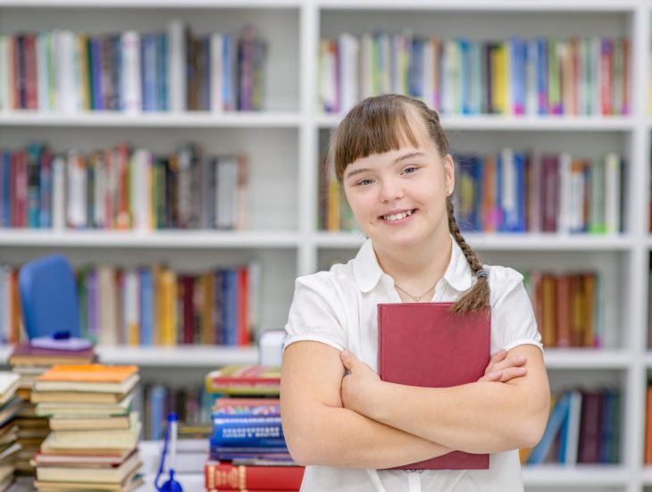 Portrait of a smiling girl with syndrome down at library. Prairie Lakes AEA Secondary Transition information.